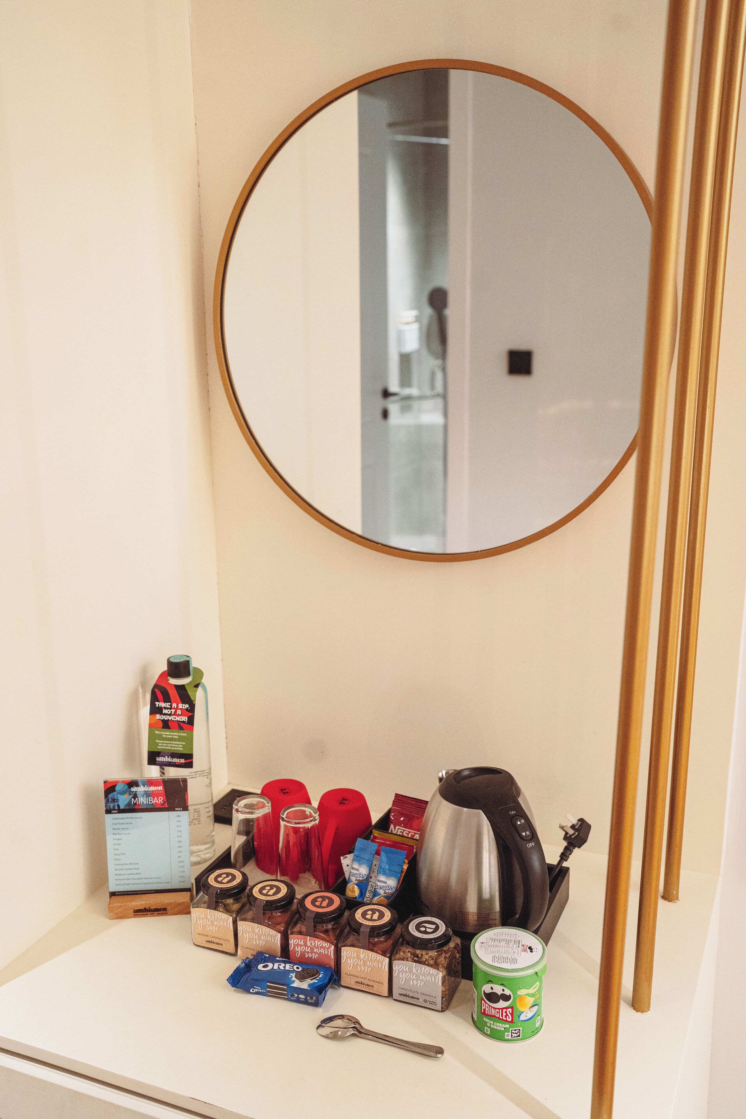 A bathroom with a round mirror, a sink, and various toiletries.