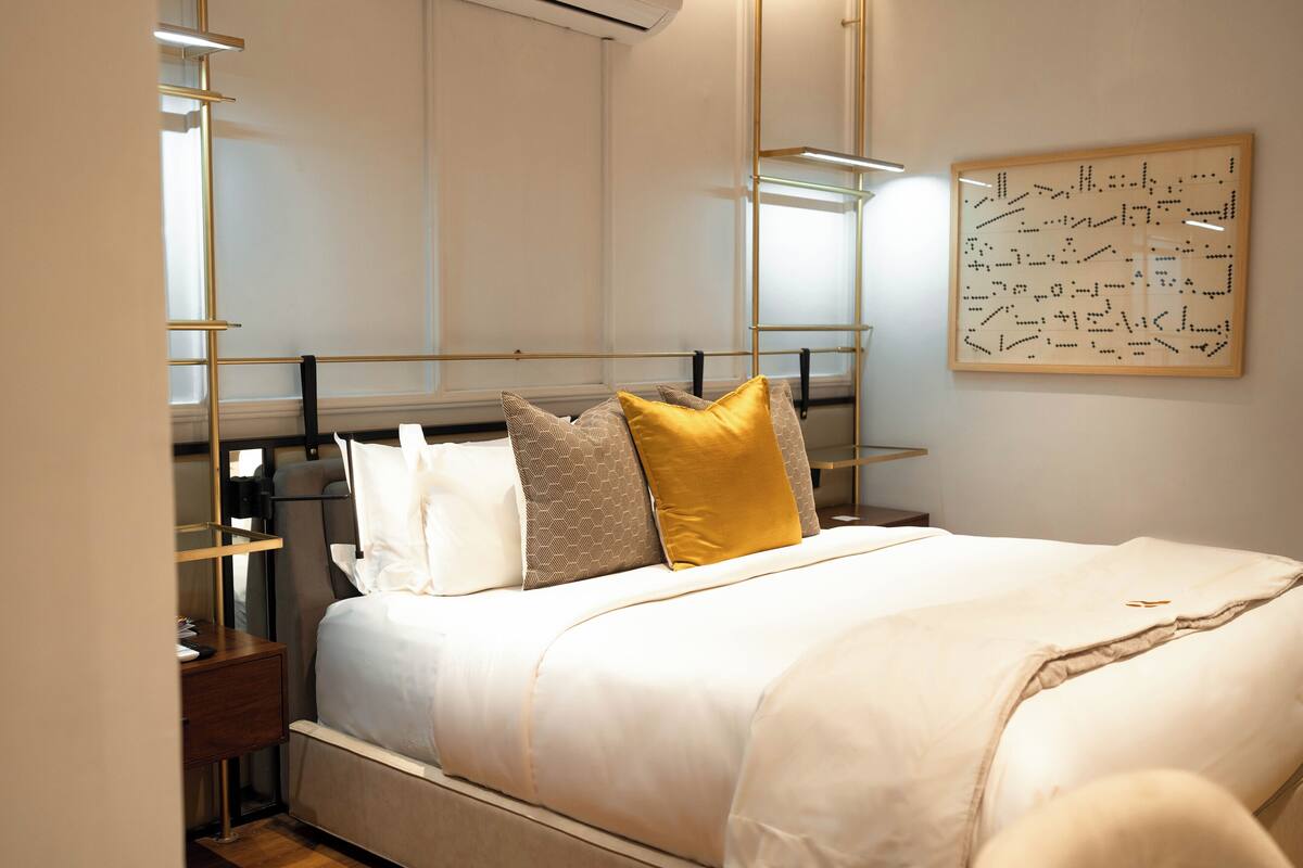 A neatly arranged bedroom with a bed, bedside tables, and a wall-mounted artwork.