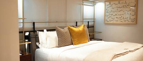 A neatly arranged bedroom with a bed, bedside tables, and a wall-mounted artwork.