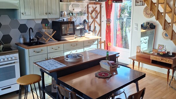 A modern kitchen with a wooden island, bar stools, and pendant lighting.
