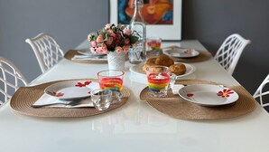 A dining table set with plates, glasses, and a vase of flowers.