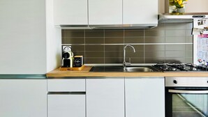 A modern kitchen with white cabinets, a stainless steel sink, a gas stove, and a built-in oven.