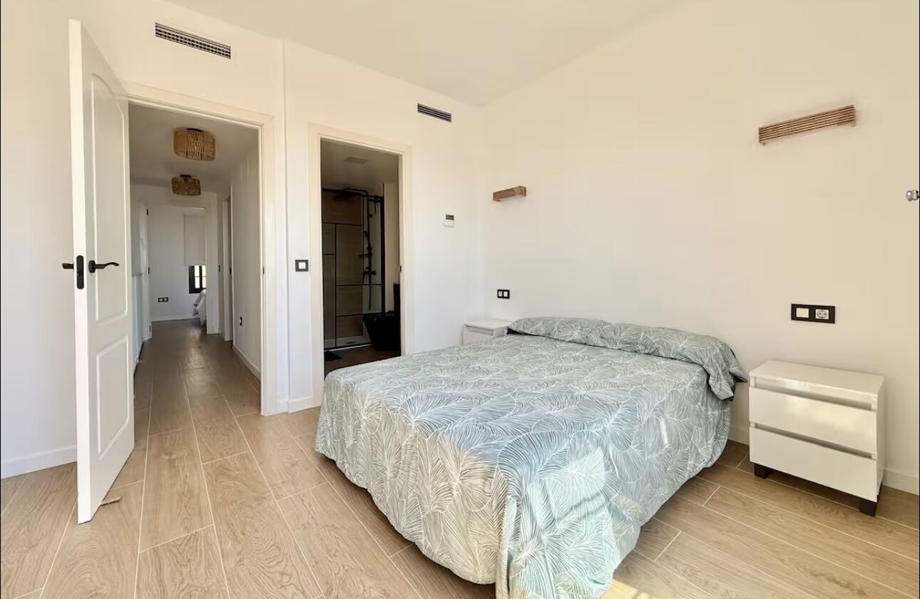 A bedroom with a bed, bedside tables, and a wardrobe.