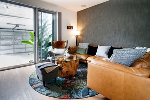 Un salon moderne avec un canapé en cuir, une table basse en verre et un tapis à motifs.
