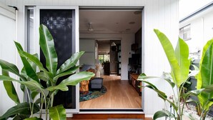 A modern house interior with a wooden floor, a dining area, and a kitchen visible through an open door. - Ohana by Khove (Miami)