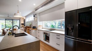 A modern kitchen with a large island, built-in appliances, and a view of greenery outside. - Ohana by Khove (Miami)