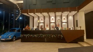 A reception desk with a modern design, featuring a dark brown counter and decorative lights. A blue car is parked outside, and the reception area is decorated with festive ornaments. - Dancenter Luxury Retreat Angeles City (Angeles City)