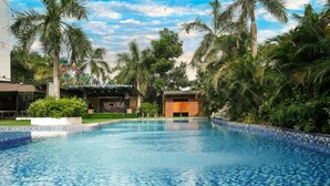 A swimming pool with a tiled edge, surrounded by palm trees and greenery. - Dancenter Luxury Retreat Angeles City (Angeles City)
