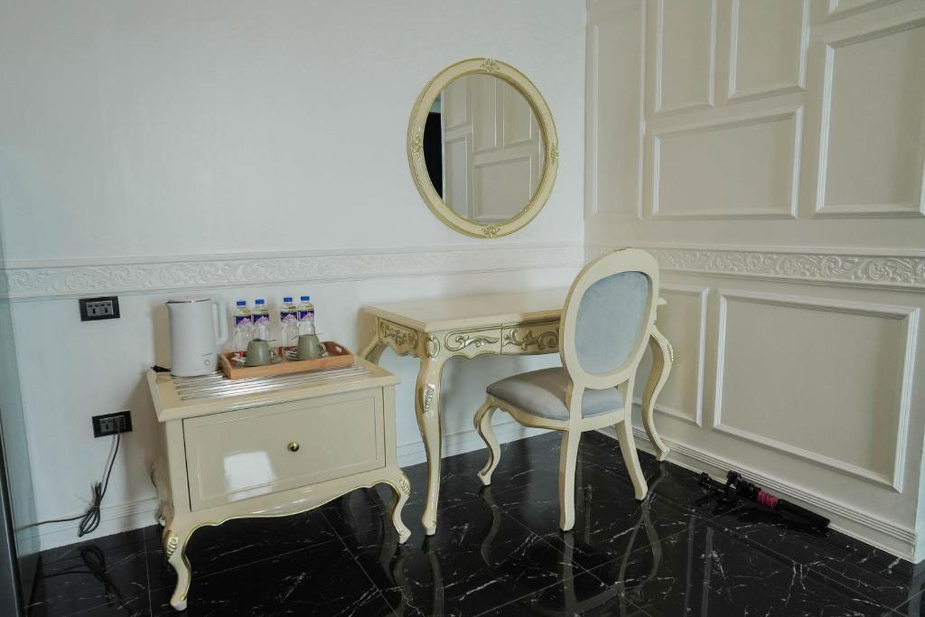 A room with a vanity, a mirror, and a desk with toiletries.