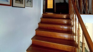 A wooden staircase with a handrail leading to a room with a door that has a window.