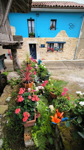 A stone building with a blue facade, a door, and windows with flower boxes. - COUNTRY HOUSE LA MAR DE LLUCES D'ÍTACA (Luces)