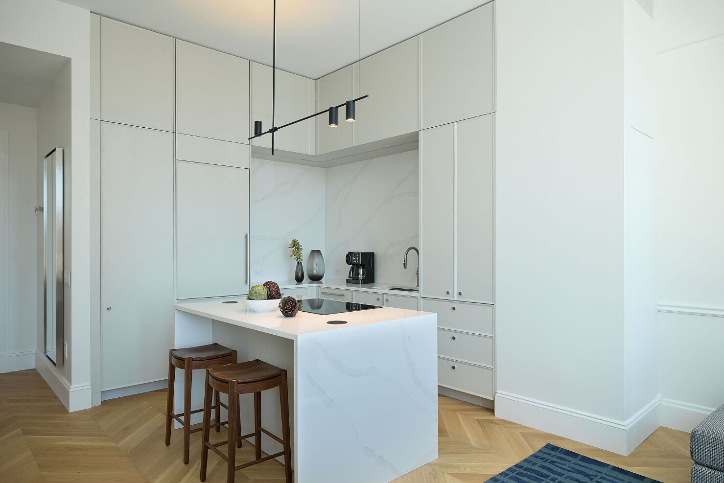 Una cocina moderna con armarios blancos, una isla central y una lámpara colgante.