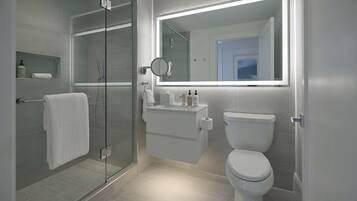 A modern bathroom with a glass-enclosed shower, a toilet, and a vanity with a mirror.