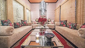 Une pièce comprenant un ensemble de canapés, une table basse ornée d’un vase de fleurs et un papier peint à motifs.