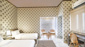 Une chambre d’hôtel avec deux lits, un coin repas avec des chaises et un appareil de climatisation.