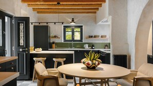 Une cuisine compacte dotée d’un îlot central, de poutres en bois au plafond et offrant une vue par une fenêtre.