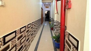 A hallway with patterned walls, a red column, and a potted plant. - suvidha guest house (Varanasi)