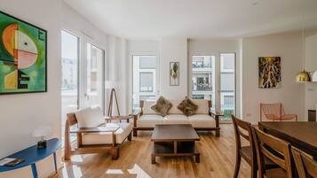 A modern living room with a sofa, chairs, a coffee table, and a dining table.