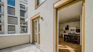 A modern apartment with a kitchen, dining area, and a balcony with a view of the building.