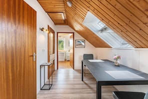 A modern interior with a wooden ceiling, a skylight, a dining table with chairs, and a view into the adjacent room. - Ostseeclick Damp – Beachside Apartment with 2 Free E-Bikes (Damp)