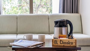 Una sala de estar acogedora con un sofá, una mesa de centro de madera, una cafetera y dos tazas blancas.