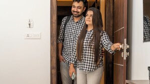 Un vano con una puerta de madera y una pared blanca, con interruptor de luz y enchufe.