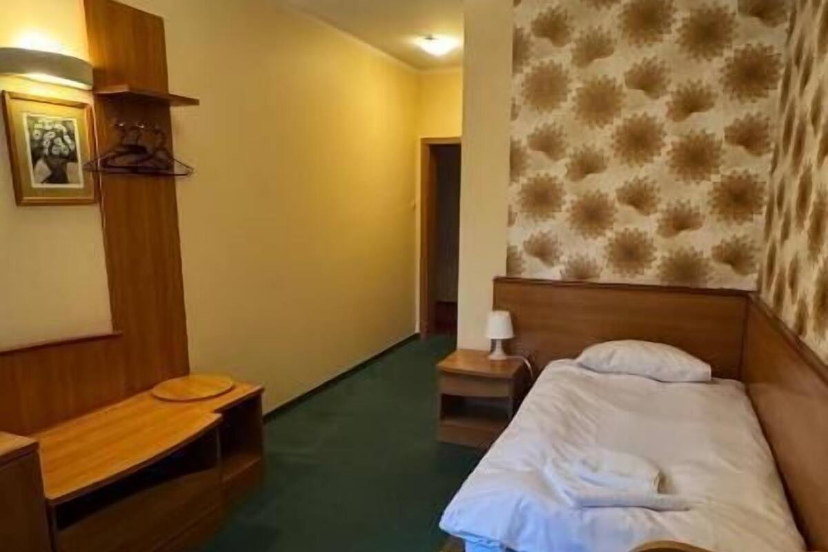 Ein Hotelzimmer mit einem Bett, einem Holztisch, einem Stuhl, einem Nachttisch und einer Wandlampe.