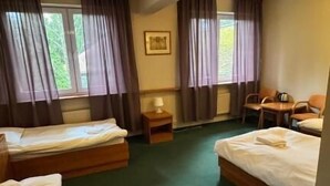 Une chambre d’hôtel avec deux lits, un bureau, des chaises et une fenêtre avec des rideaux.