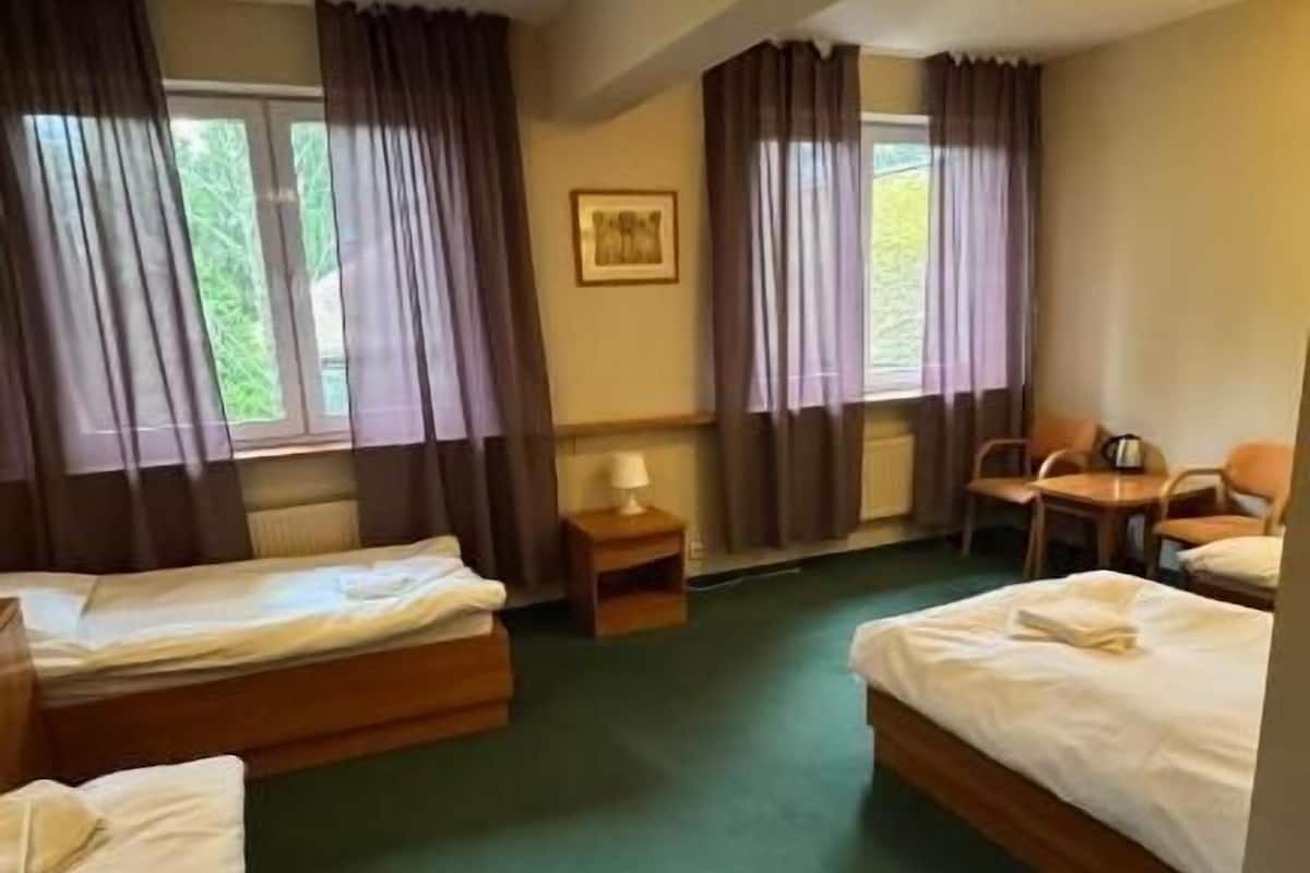Ein Hotelzimmer mit zwei Betten, einem Schreibtisch, Stühlen und einem Fenster mit Vorhängen.