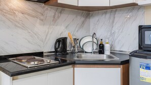 A modern kitchen with a marble backsplash, a built-in stove, a sink, and a refrigerator. - Queen Studio, City View - Virgo Nest Rentals (Cebu City)