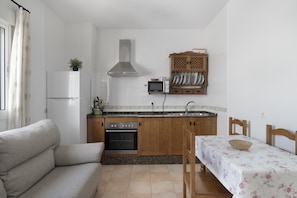A compact kitchen with a built-in oven, microwave, and a wooden cabinet above the sink.