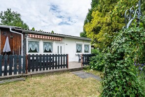 Une maison de plain-pied avec un porche, une cour clôturée et un jardin.