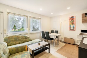 Une pièce comprenant un canapé, une table à manger, des chaises, un radiateur et un téléviseur.