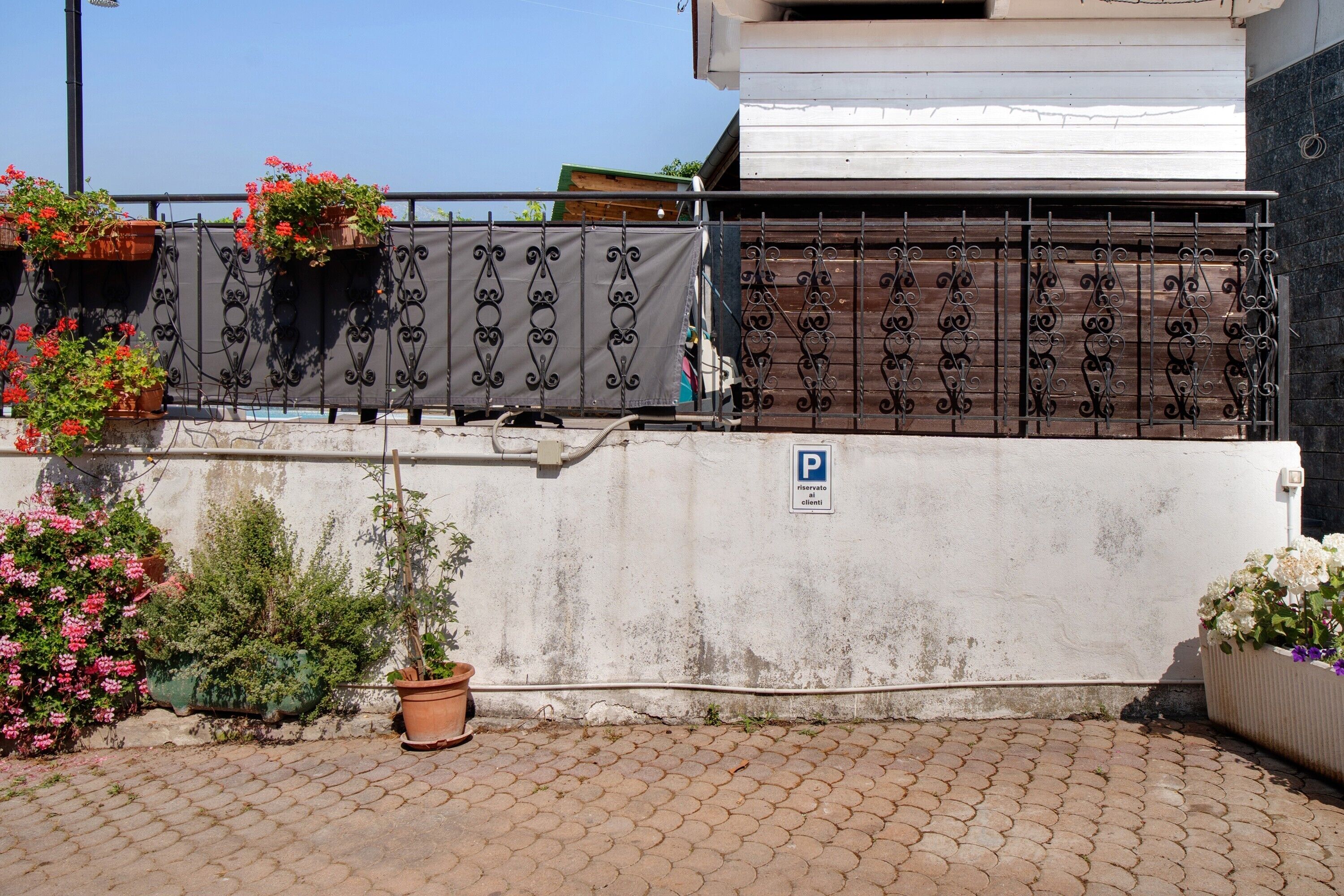 A gated area with a parking sign, potted plants, and a paved walkway.