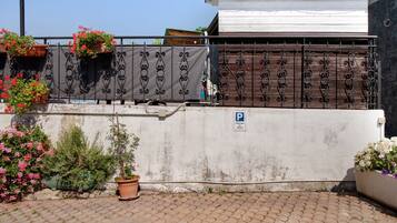 A gated area with a parking sign, potted plants, and a paved walkway.