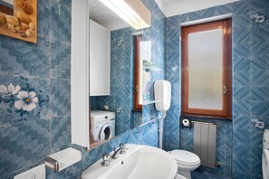 Un baño con lavamanos, inodoro y espejo.