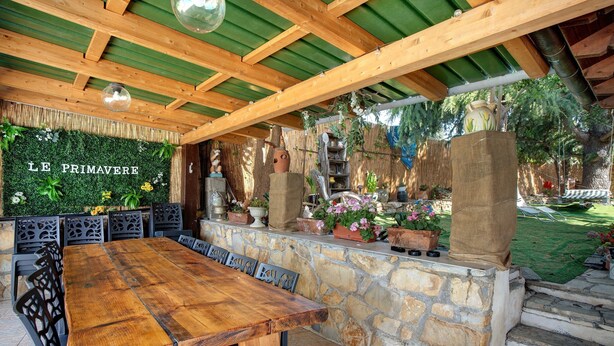 Un espace extérieur aménagé avec un mur en pierre, une table en bois et des chaises.