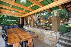 Un área de estar al aire libre con pared de piedra, mesa y sillas de madera.