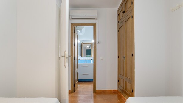 A narrow hallway with two beds on either side, leading to a bathroom with a mirror and a sink. - Apartment 'Atardecer En Conil 2' with Air Conditioning (Conil de la Frontera)