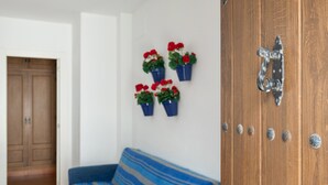 A room with a wooden door, a blue-striped sofa, and potted plants on the wall. - Apartment 'Atardecer En Conil 2' with Air Conditioning (Conil de la Frontera)