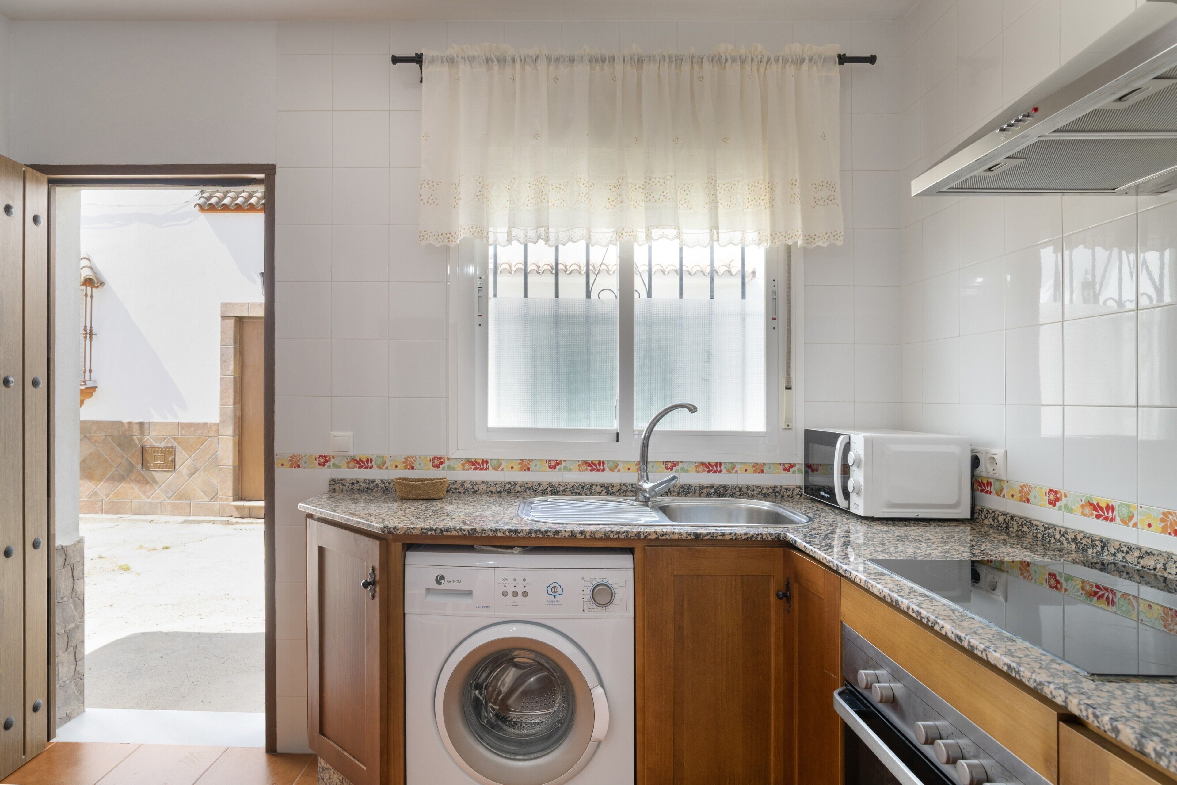 A compact kitchen with a washing machine, a sink, and a toaster.