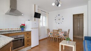 A compact kitchen with a stove, oven, and a TV mounted above the counter. - Apartment 'Atardecer En Conil 2' with Air Conditioning (Conil de la Frontera)