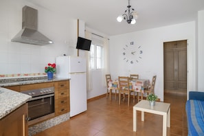 A compact kitchen with a stove, oven, and a TV mounted above the counter.
