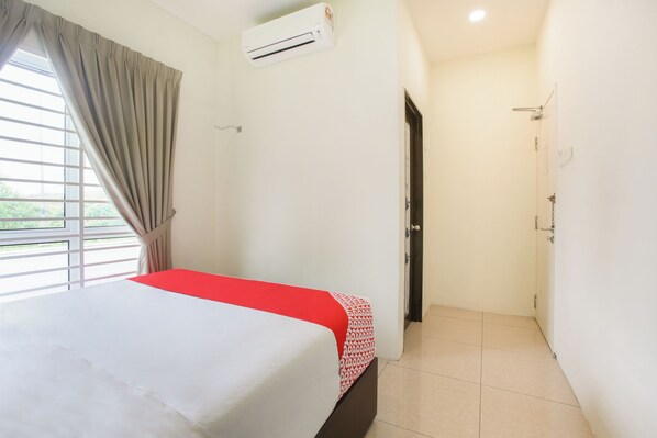 A hotel room with a bed, a window with curtains, an air conditioning unit, and a door leading to a bathroom. - Junction Hostel Poblacion Makati Avenue (Makati)
