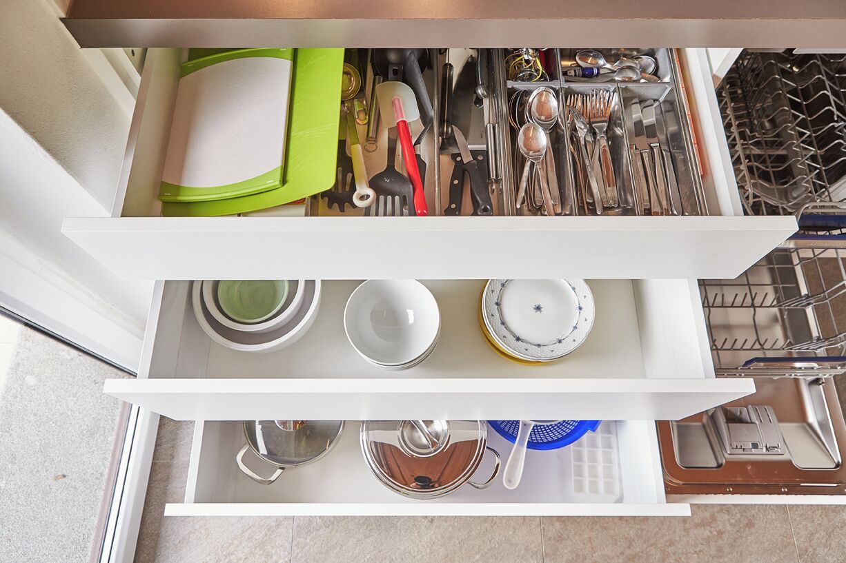Un cajón de cocina con utensilios, platos y un escurreplatos.