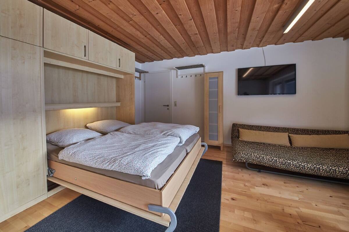 Une chambre à coucher avec un lit en bois, une armoire intégrée et un canapé.