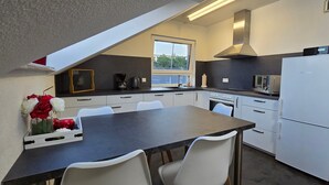 Una cocina moderna con comedor, que incluye una mesa, sillas y un refrigerador.