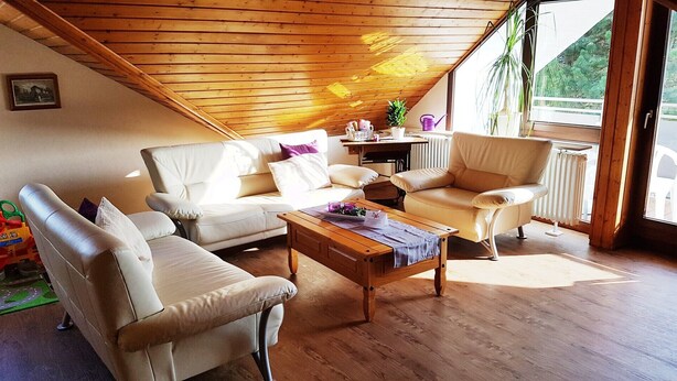 Un salón acogedor con techo de madera, un sofá, un sillón y una mesa de centro.