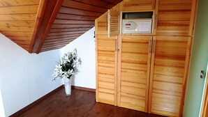 Un mueble de madera con un microondas, un florero de vidrio con flores y un techo de madera.