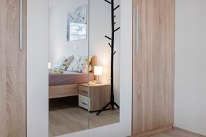 A bedroom with a bed, bedside table, lamp, and a coat rack. - Studio 'Karlsplatz' with Wi-Fi (Freiamt)